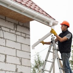 man inspecting downspout